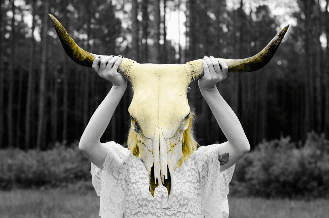 A woman with a cow skull on her head attending a marketing workshop.