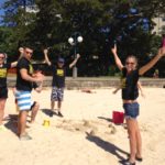 A group of people playing frisbee on the sandy beach.
