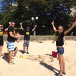 A group of people playing frisbee on the sandy beach.