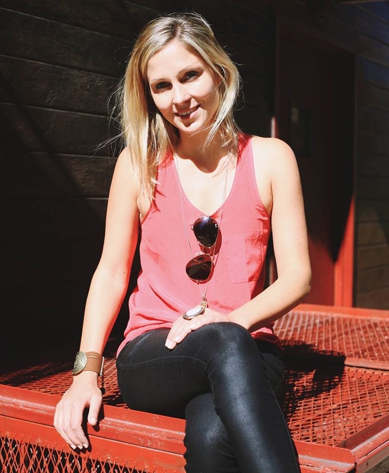 A blonde woman in a red tank top sitting on a red bench.
