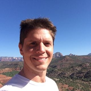 A man taking a selfie in front of a mountain, practicing small business marketing.