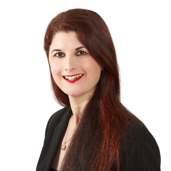 A woman with long red hair in a black suit attending a marketing workshop.
