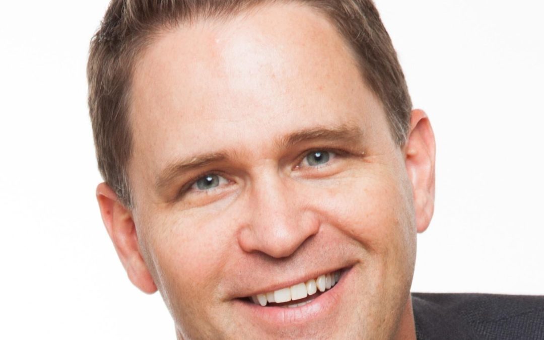 A man in a suit and tie smiling while presenting a marketing plan during a small business marketing workshop.