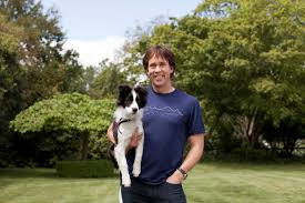 A man holding a dog in a grassy yard during a marketing workshop.