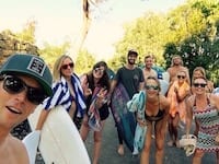 A group of people participating in a marketing workshop, posing for a photo with their surfboards.