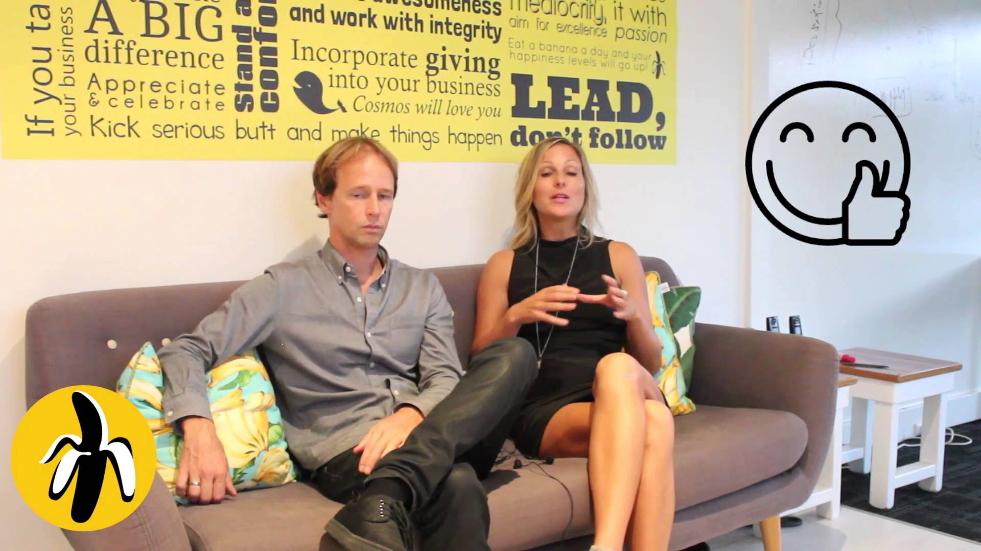 Two people participating in a marketing workshop, sitting on a couch in front of a yellow wall.