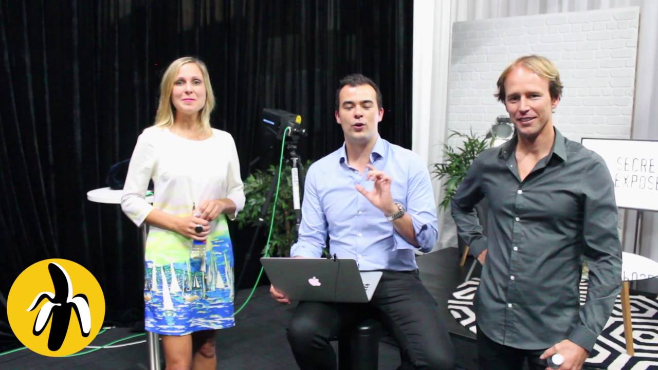 Three people sitting on a stage during a marketing workshop with a laptop in front of them.