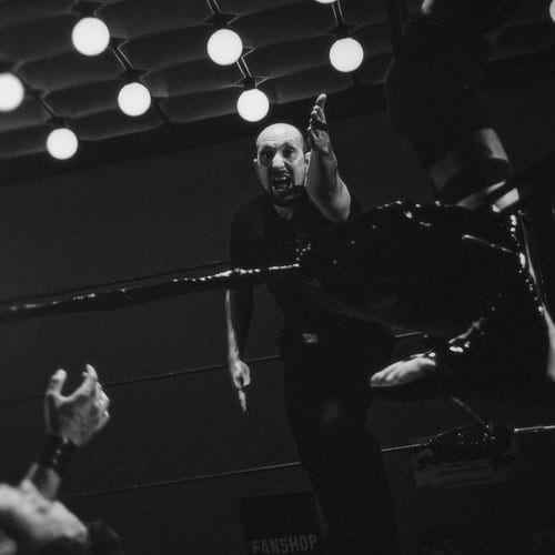 A black and white photo of a wrestler in the ring, capturing the intense action and charisma.