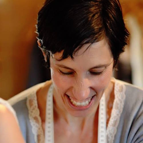 A woman smiles while cutting a cake in a kitchen during a small business marketing workshop.