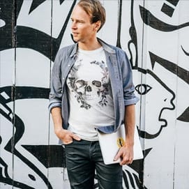 A man in jeans and a t-shirt standing in front of a graffiti wall during a marketing workshop.