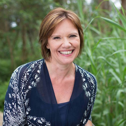 A woman smiling in front of tall grasses, showcasing her small business marketing expertise and mentoring skills acquired through a marketing workshop.