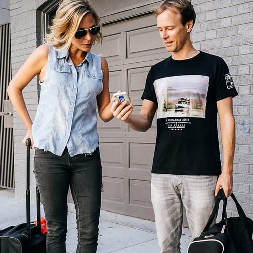 A couple holding luggage in front of a garage, participating in a marketing workshop.