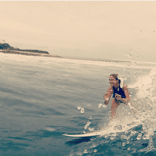 A woman riding a wave on a surfboard, seeking mentoring for small business marketing.