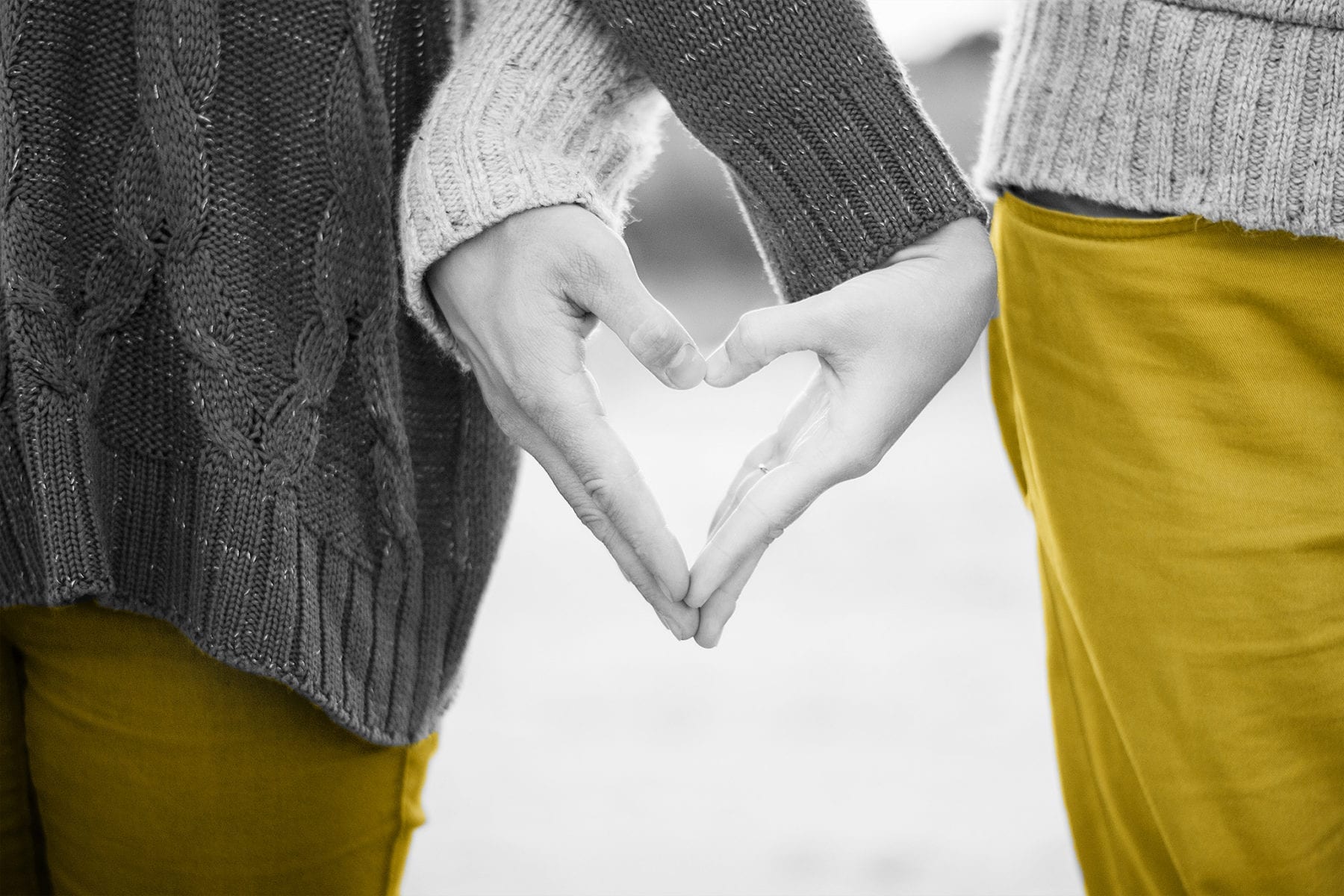 Black and white photo of a couple making a heart shape with their hands at a marketing workshop.