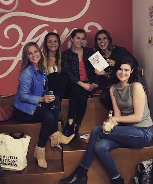 A group of women attending a marketing workshop, posing for a photo in front of a sign.