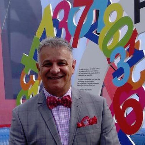 A man in a suit standing in front of a large number sign while conducting a marketing workshop.