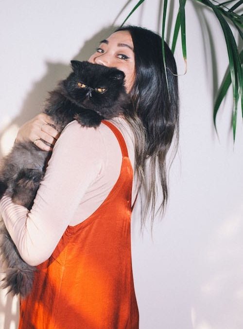 A woman holding a black cat in front of a plant participates in a marketing workshop, gaining valuable mentoring for her small business marketing strategies.