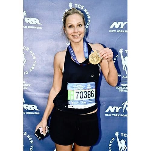 A woman holding a medal in front of a small business marketing workshop backdrop.