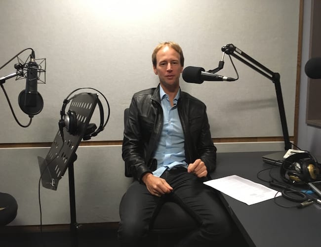 A man sitting in front of a microphone conducting a marketing workshop.