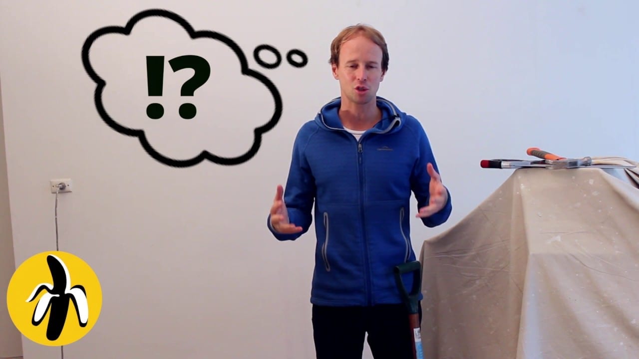 A man standing in front of a question mark-adorned wall during a marketing workshop.