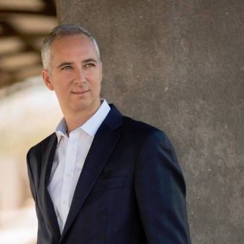 A man in a suit leaning against a wall, facilitating a marketing workshop.