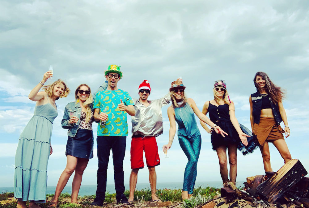 A group of people posing for a photo on the beach during a marketing workshop.