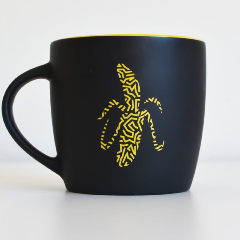 A black and yellow A Cuppa Genius with a banana on it, perfect for small business marketing.
