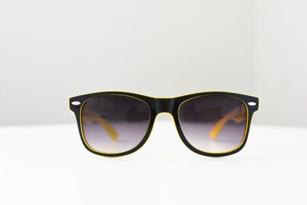 A pair of I See You Sunglasses, yellow and black, on a white surface, perfect for small business marketing.