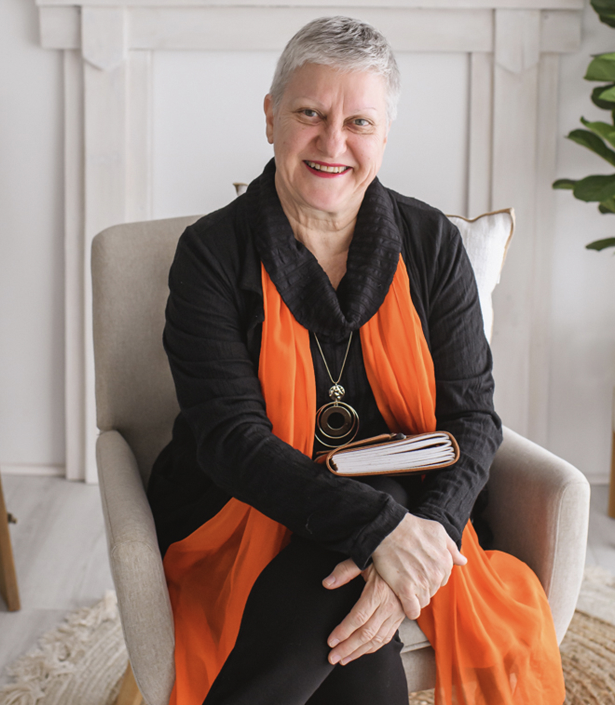 An older woman sitting in a chair holding a book.