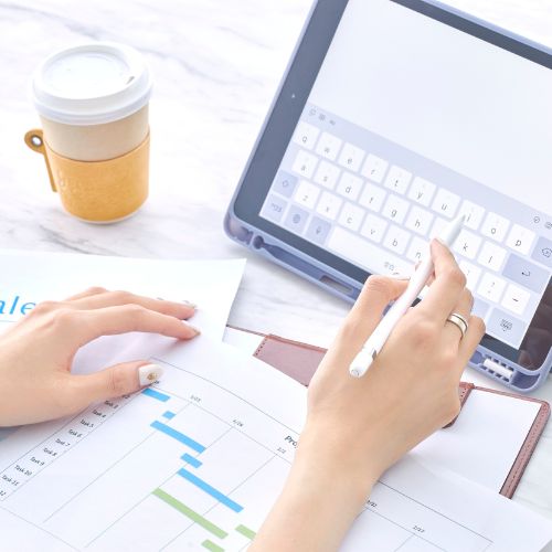 Person using a stylus to type on a tablet, with documents and a chart on the desk, and a takeaway coffee cup nearby. Person using a stylus to type on a tablet, with documents and a chart on the desk, and a takeaway coffee cup nearby.